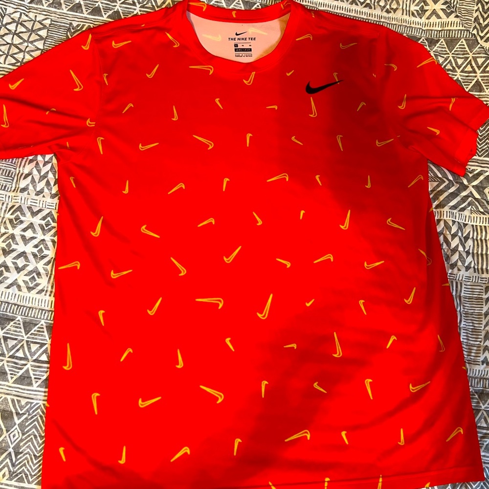 Nike Dri-Fit red tee with bold black swoosh logo and all-over gold swoosh